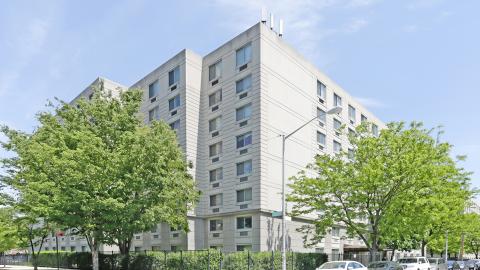 Two eight-story buildings with a white facade stand tall in Corona, Queens.